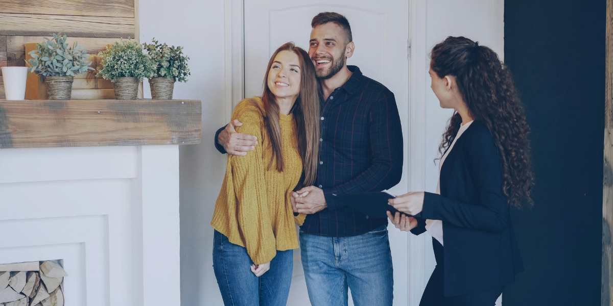A happy young couple viewing a residential property with a real estate agent, serving as a contrast to higher deposit requirements found in commercial real estate investments.