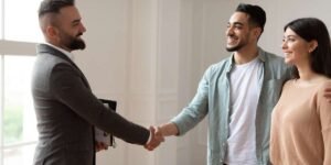A professional commercial mortgage broker smiling and shaking hands with a young couple, completing a consultation for a limited company buy to let mortgage.