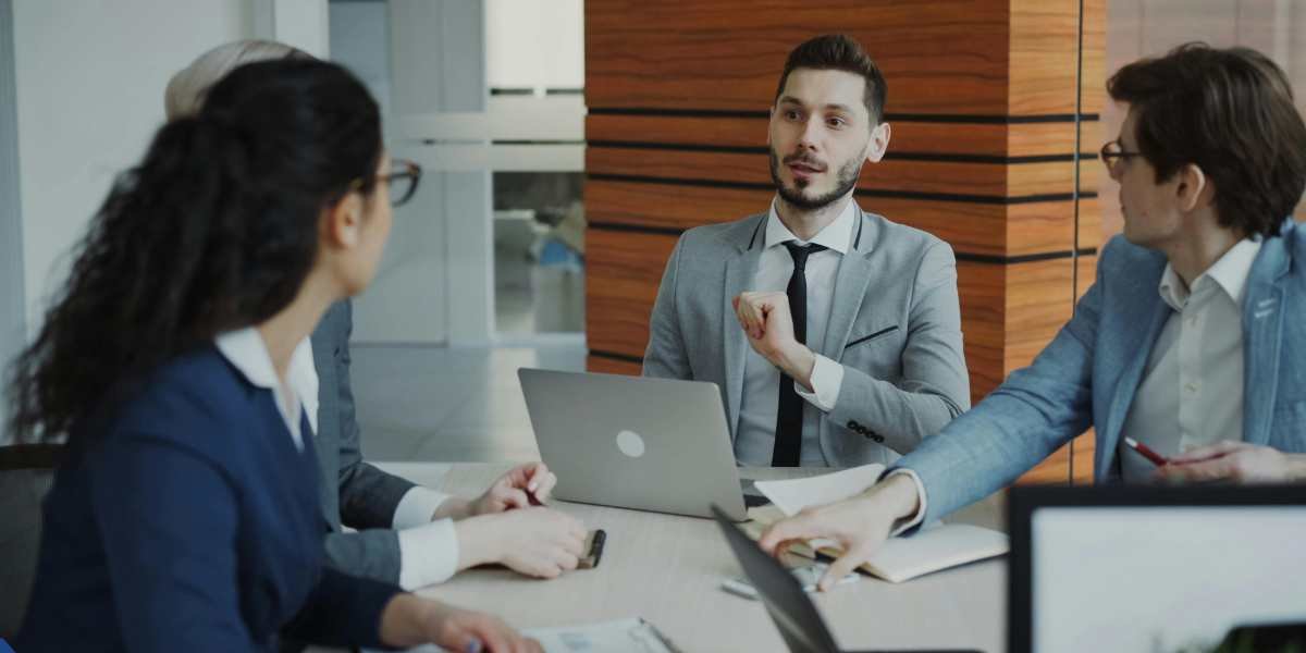 A professional male business consultant leading a meeting with startup entrepreneurs in a modern boardroom, discussing options for securing a commercial mortgage.