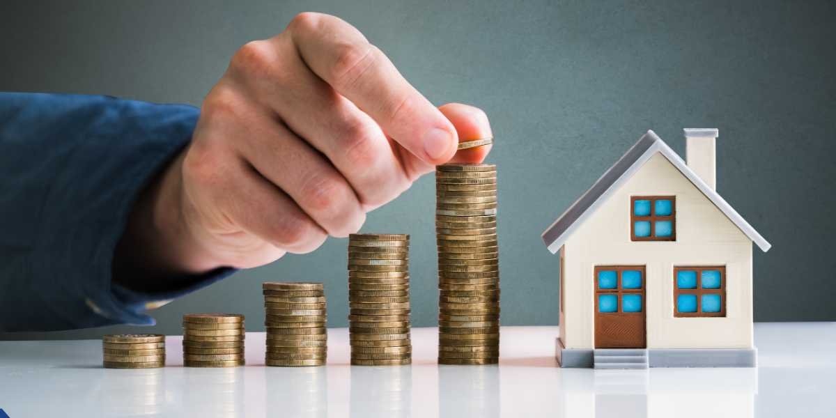 A hand stacking gold coins next to a small model house, representing the hidden property investment and maintenance costs for first-time landlords.