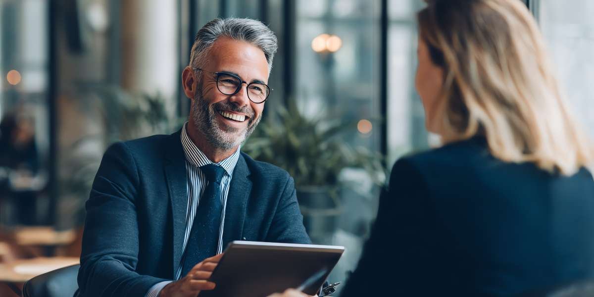 A smiling professional finance broker or consultant discussing how a bridging loan works in the UK with a client during a face-to-face consultation.
