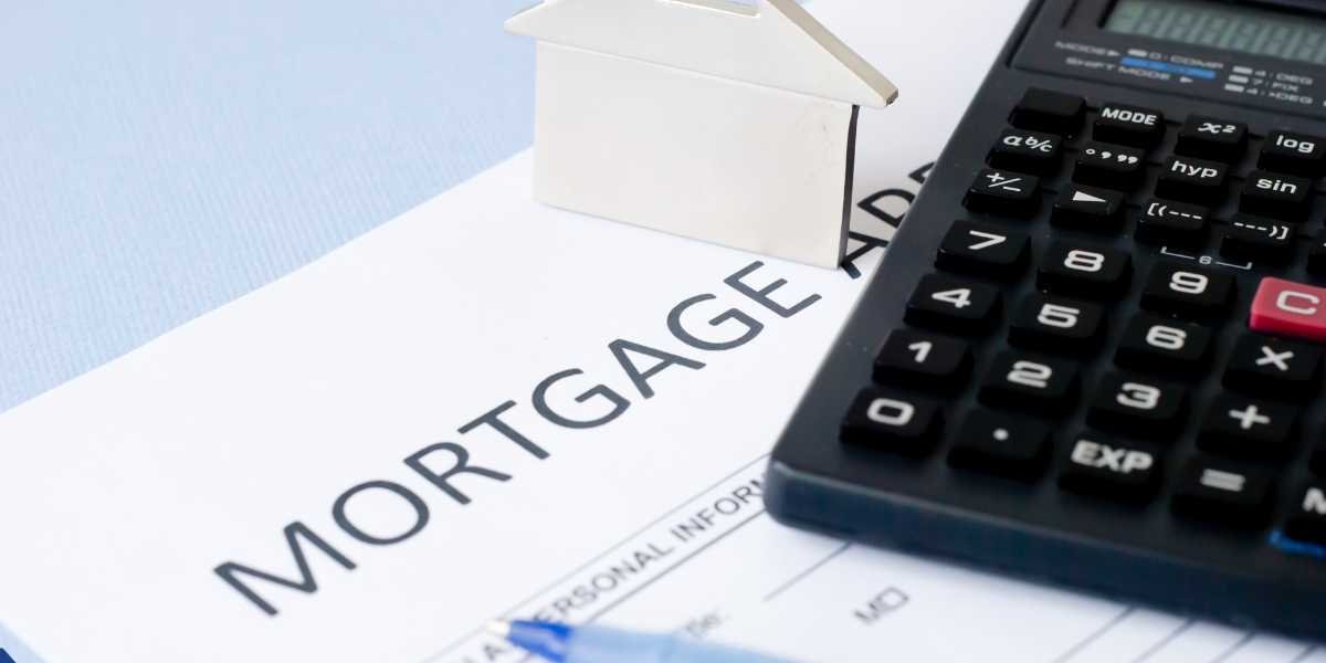 A close-up view of a document with the word "MORTGAGE" printed across it. A black scientific calculator rests on the right side of the paper, and a small white paper cutout of a house stands upright on top of the document.