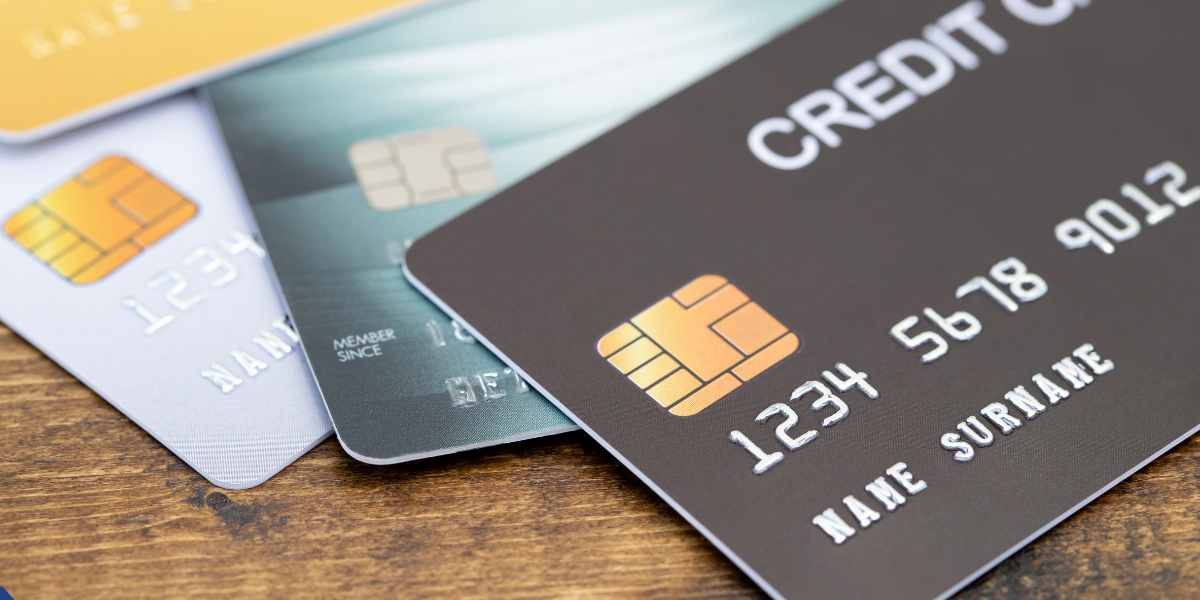 Close-up of a stack of multiple credit cards on a wooden surface, highlighting the consumer credit card debt that lenders evaluate during a mortgage application.
