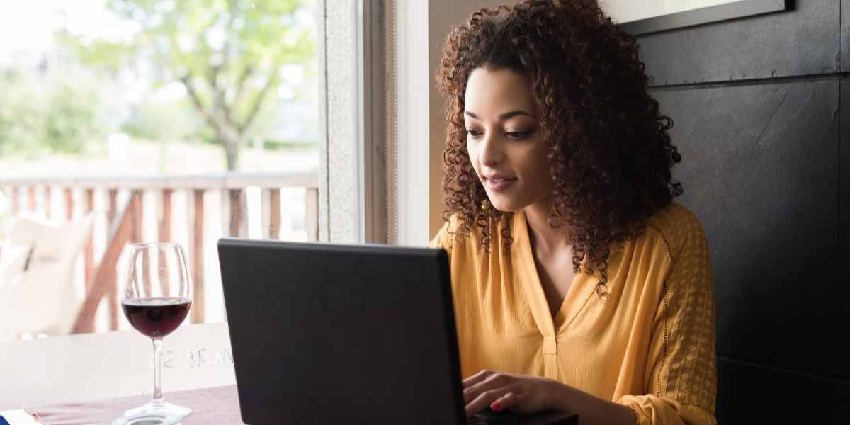 A self-employed business owner with curly hair working on her laptop at a table, symbolizing local Enfield entrepreneurs managing their mortgage applications.