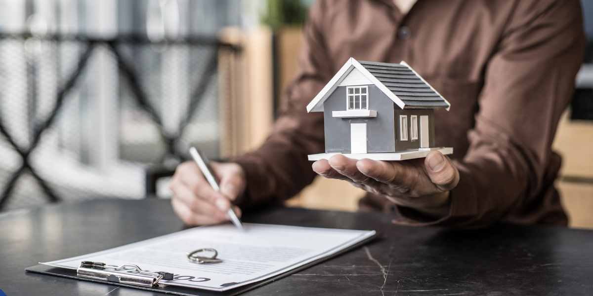 Close-up of a mortgage advisor in Enfield holding a small house model over a clipboard, illustrating expert mortgage guidance for self-employed clients.