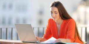 A young self-employed woman working on her laptop outdoors, representing local Enfield freelancers researching mortgage options.