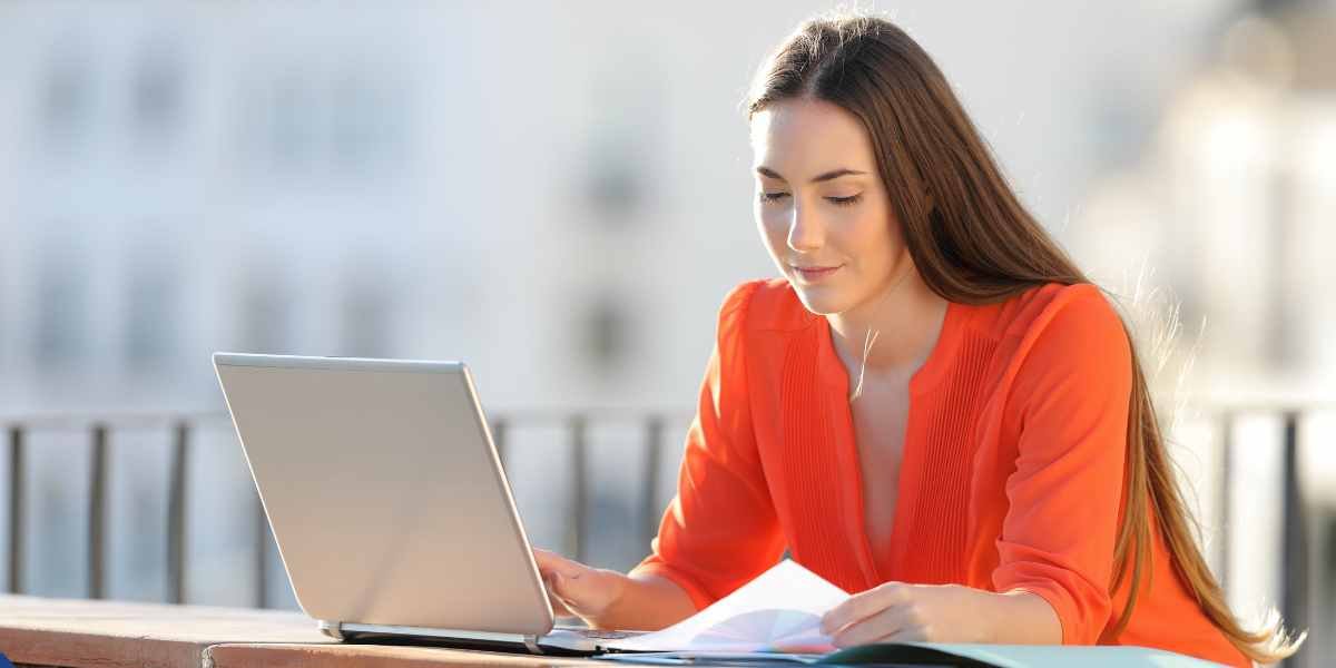 A young self-employed woman working on her laptop outdoors, representing local Enfield freelancers researching mortgage options.