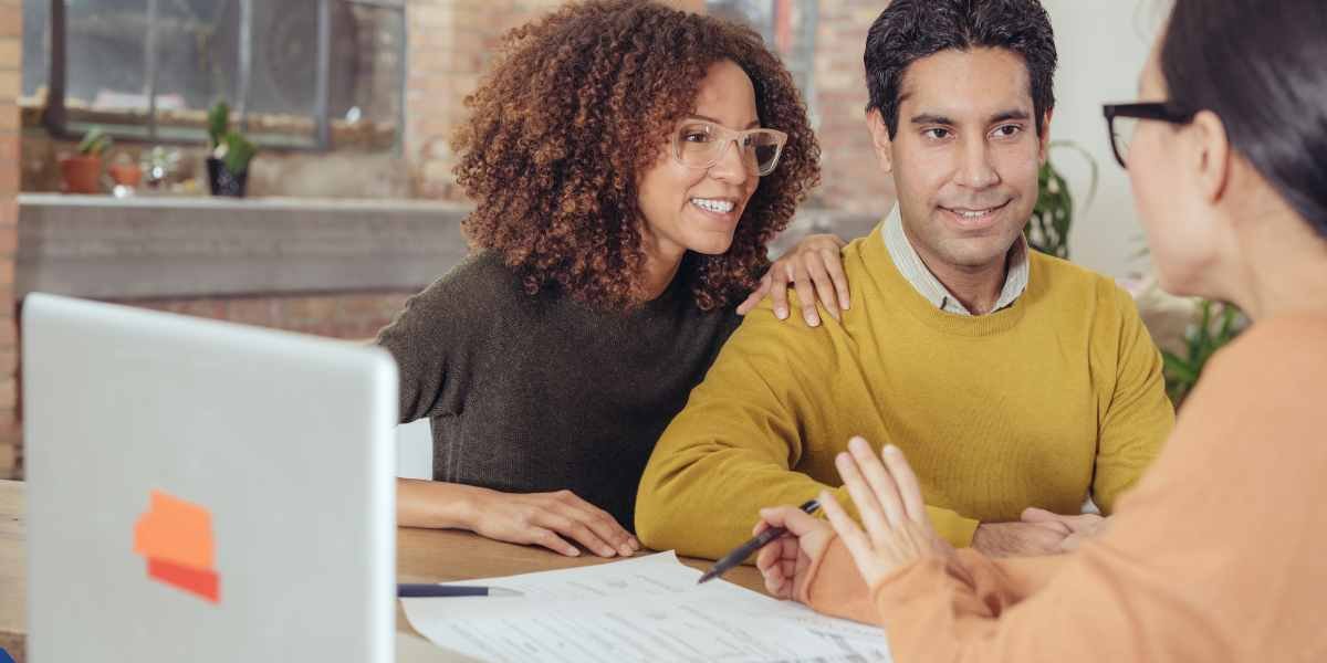 A young couple sitting with a mortgage advisor in Enfield, discussing home loan options and reviewing financial paperwork for their first property purchase.