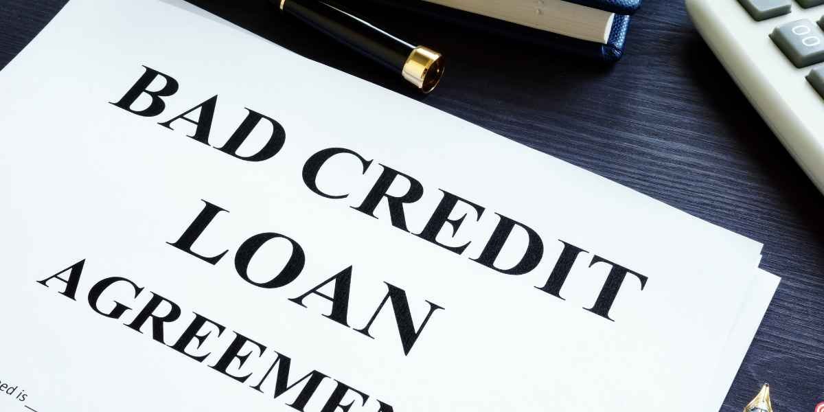Close-up of a printed document titled Bad Credit Loan Agreement with a pen and calculator nearby.